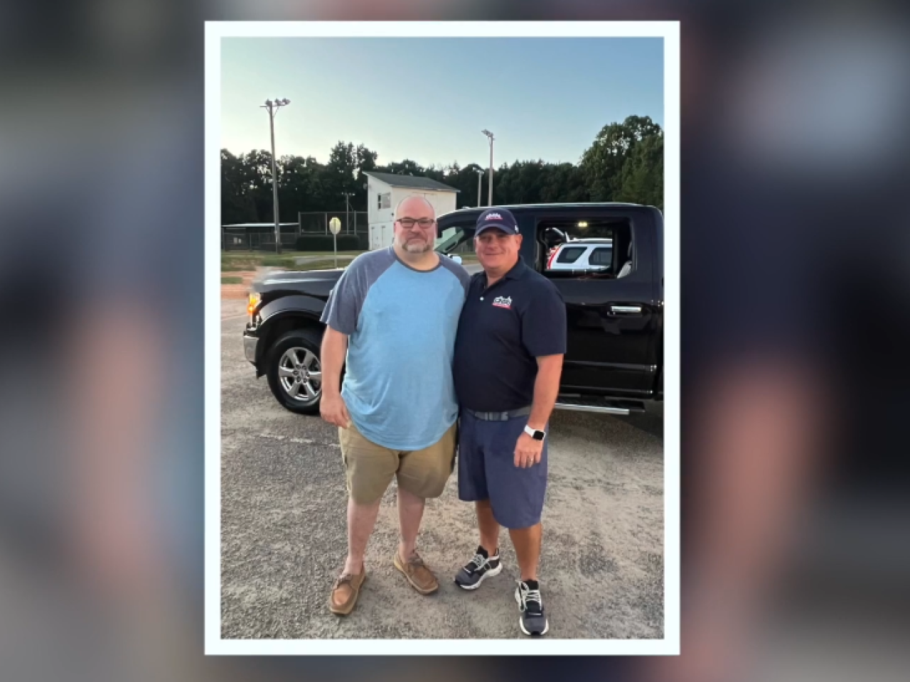 two men standing together in front of truck