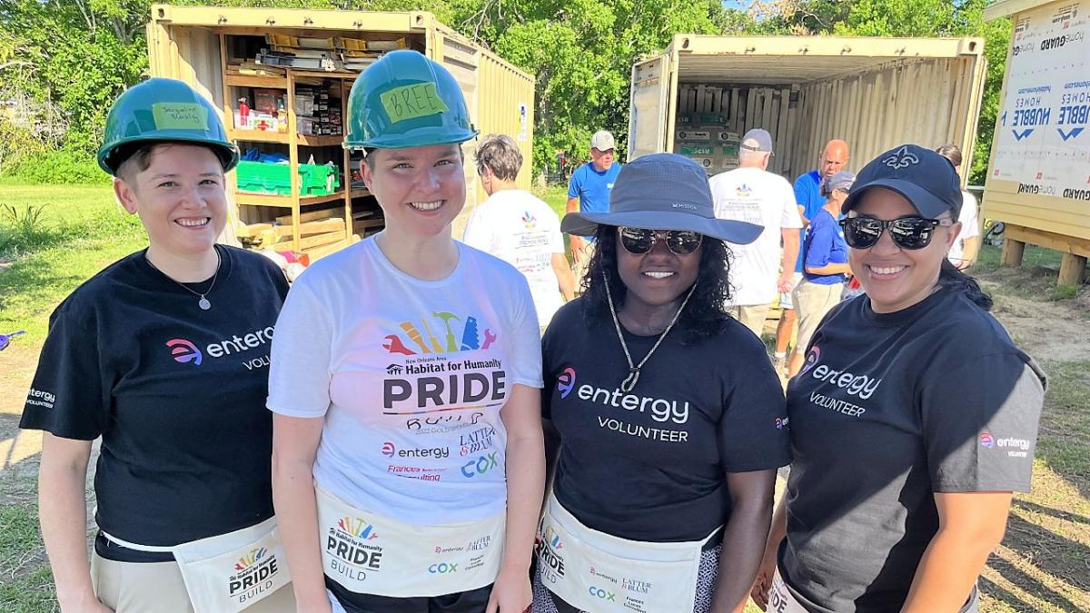 Entergy volunteers in hard hats with one in a Habitat for Humanity t-shirt